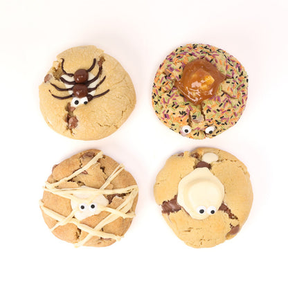 Four Halloween-themed decorated cookies arranged in a 2x2 grid on a white background. The top-left cookie is tan with a dark brown spider decoration and white eyes.