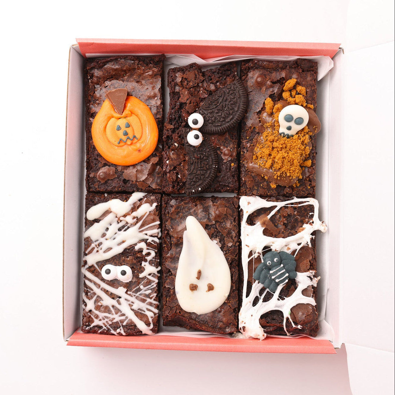 Box of Halloween-themed brownies with decorative elements on a white background